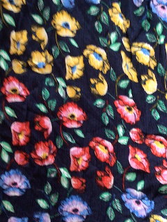 Colorful floral pattern with red, yellow, pink and blue flowers on dark navy fabric