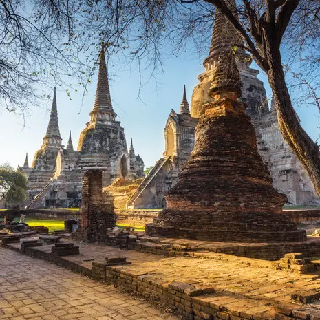 Ancient temple stupas and brick ruins in Ayutthaya, Thailand, under a blue sky