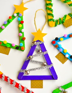 Handmade Christmas tree ornaments with beads, glitter, pompoms and stars arranged on white surface