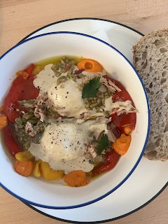 Plate with two poached eggs, vegetables, herbs, and a slice of bread