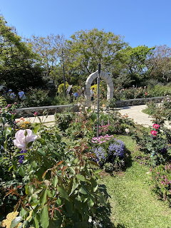Garden with roses, flowering shrubs, and an arched trellis on a sunny day