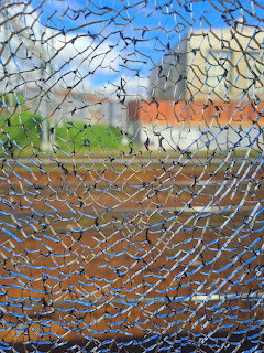 Rural landscape seen through heavily cracked and shattered glass creating abstract web pattern
