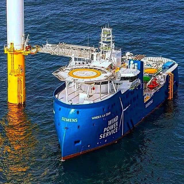 Blue offshore service ship Windea La Cour beside a yellow platform on the sea