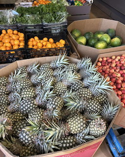 Market stall with pineapples, citrus fruits, and vegetables in wooden containers