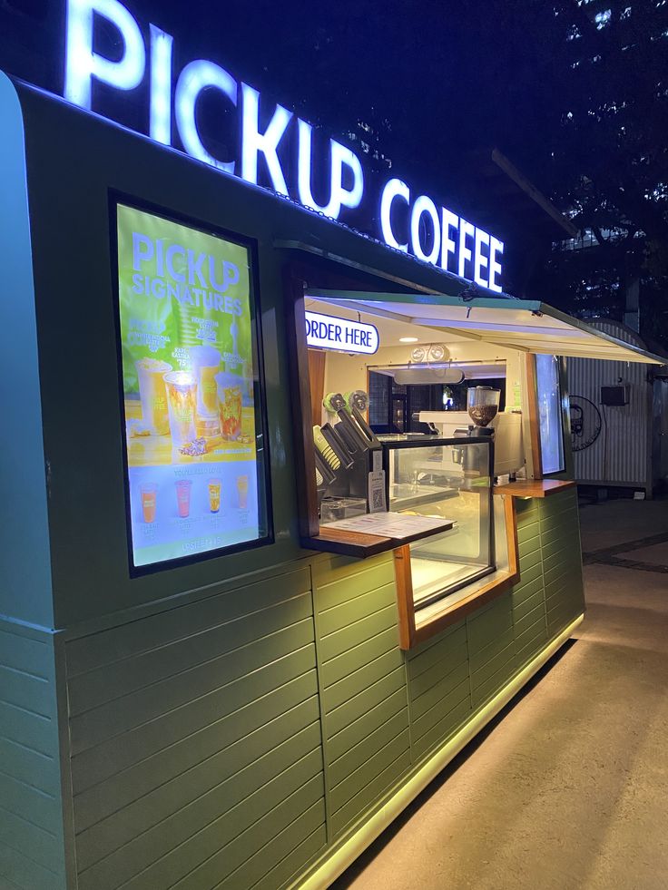 Pickup Coffee cafe storefront illuminated at night with customers outside