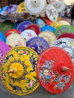 Decorative Thai paper umbrellas with painted floral designs in bright colors at an outdoor market
