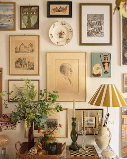 Vintage-style interior with framed artwork, table lamp, plants, and decorative objects
