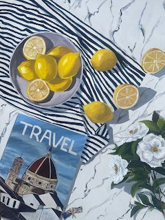 Overhead view of yellow lemons in bowl, travel magazine, and white flowers on striped fabric