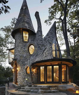 Fairytale stone house with pointed tower roofs and warm lit windows among trees at twilight