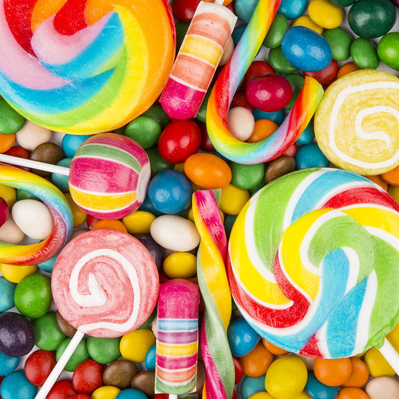 Assorted colorful candies including spiral lollipops, gumballs, and striped candy canes