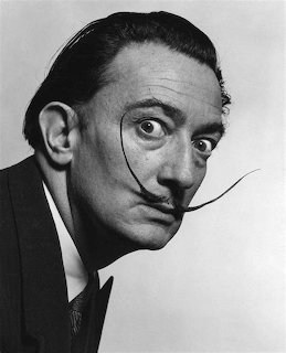 Black and white portrait photo of Salvador Dalí with his signature upturned mustache
