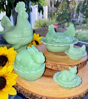 Green jadeite glass animal figurine bowls and lids on wooden display rounds with yellow sunflowers