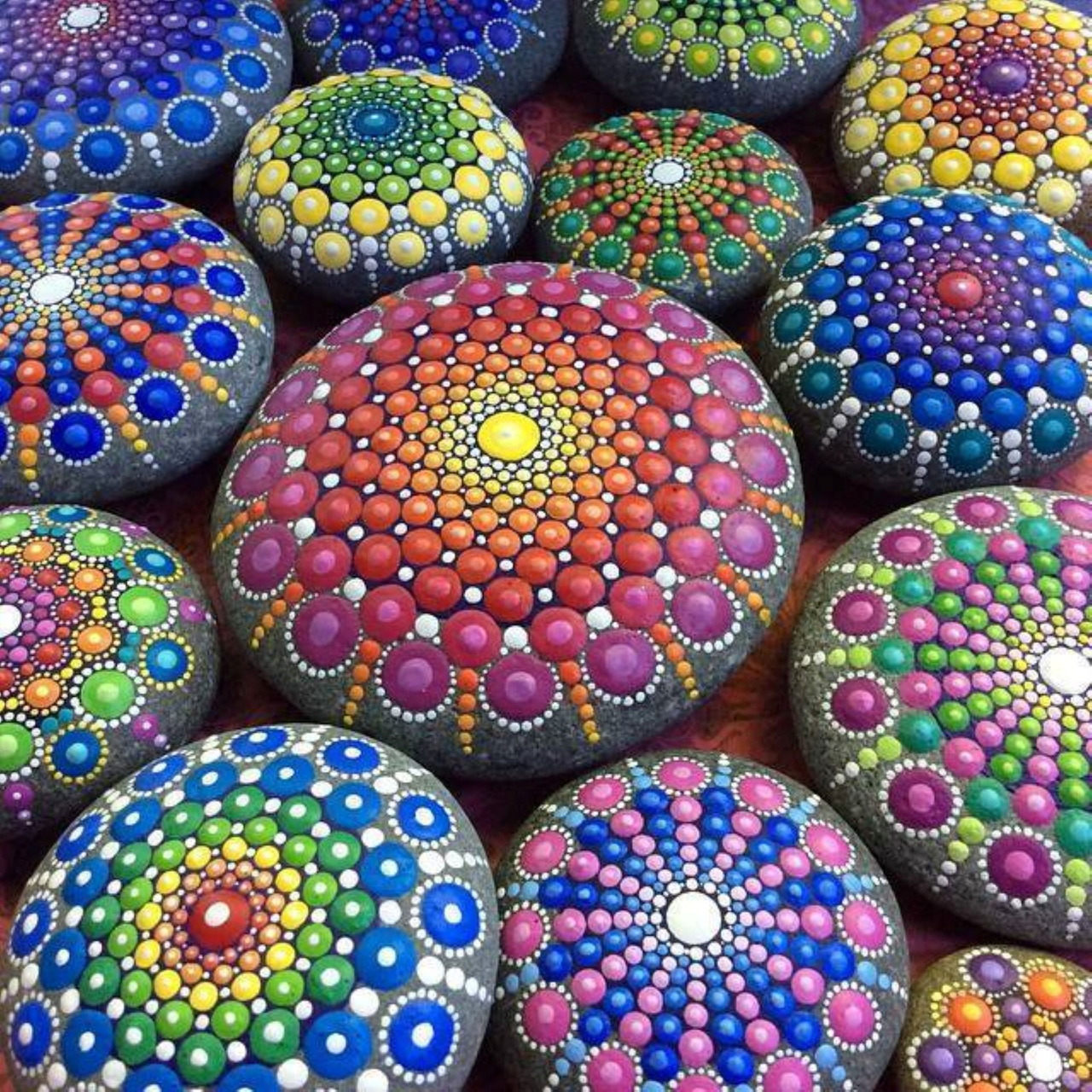 Colorful hand-painted rocks with intricate dot mandala patterns in various colors