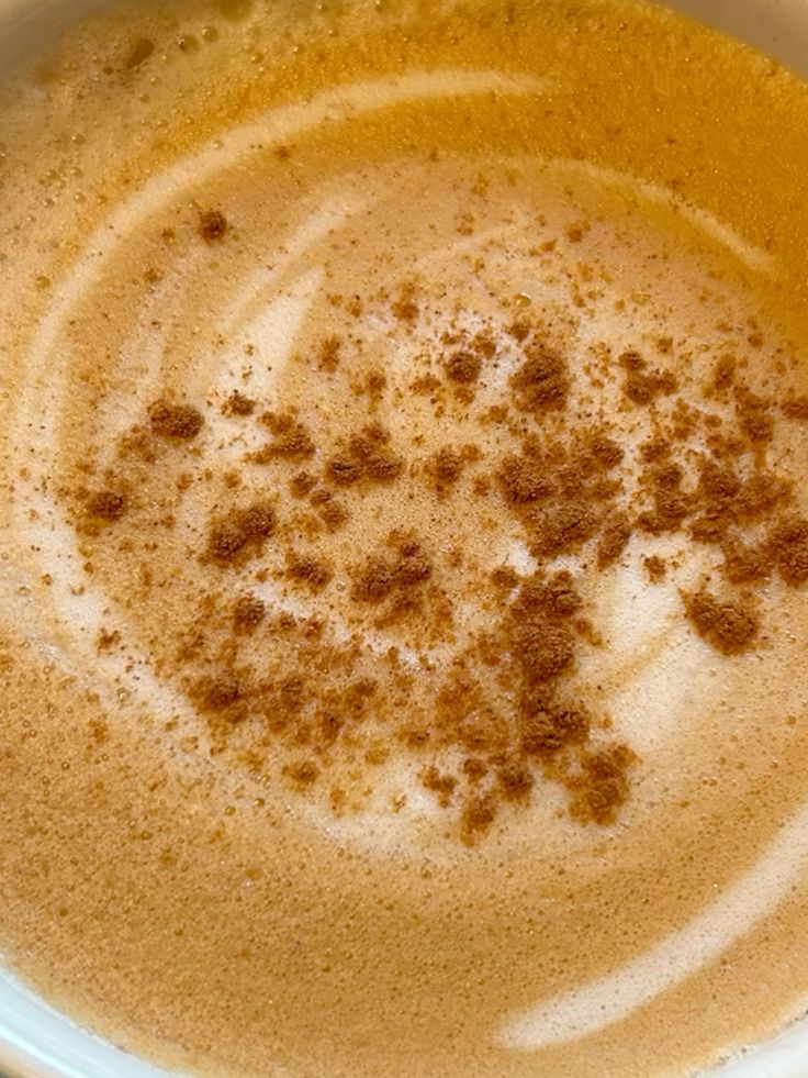Overhead view of cappuccino with foam swirls and cocoa powder in white cup