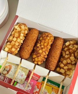 Korean street food box with corn dogs and fried snacks with sauce packets