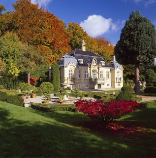 Baroque castle with formal garden, autumn foliage, and red flowers in foreground