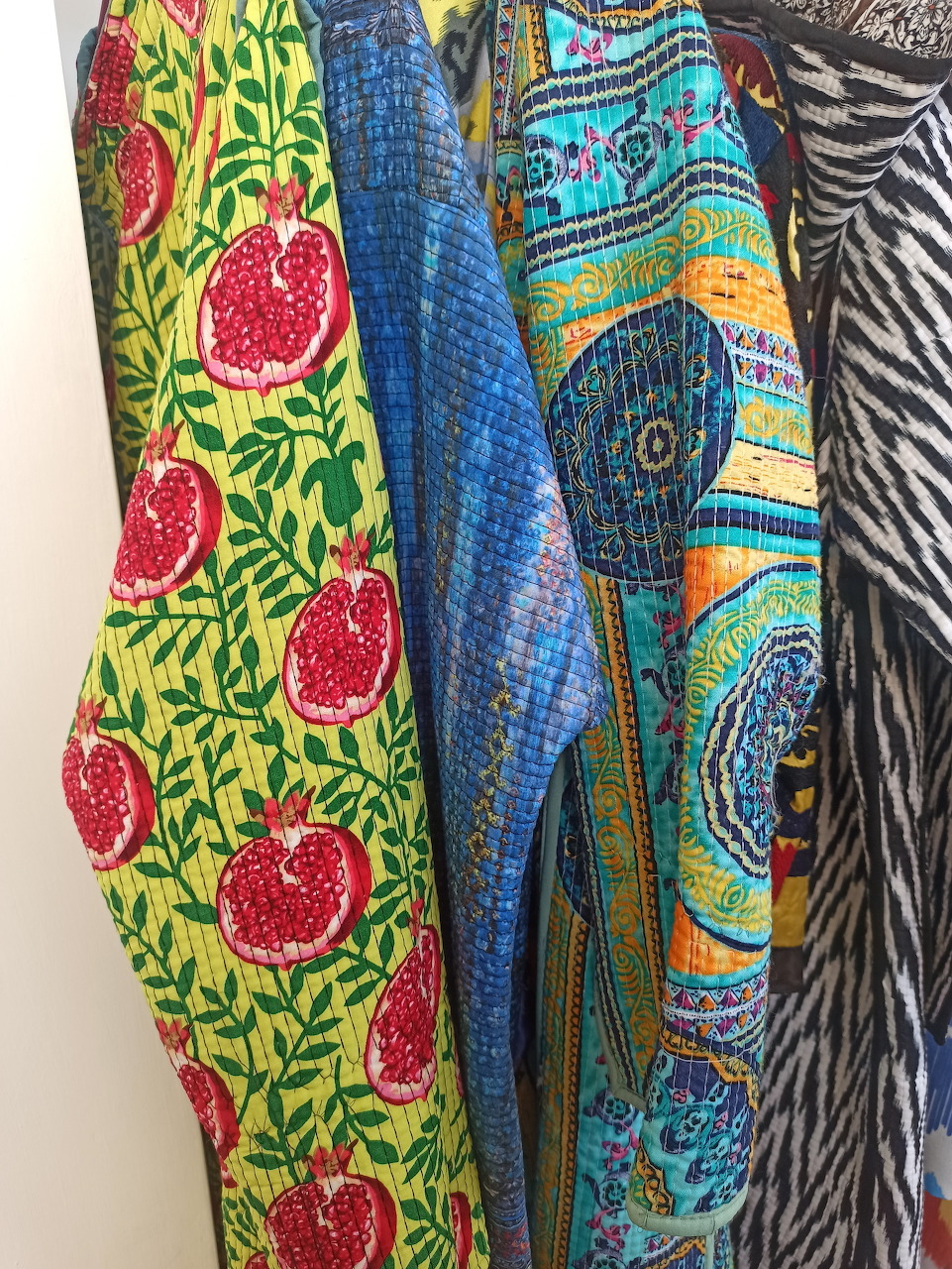 Close-up of hanging colorful patterned fabrics with pomegranate, paisley, and zebra-style prints