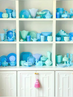 White shelves filled with blue and turquoise milk glass dishes and decorative pieces