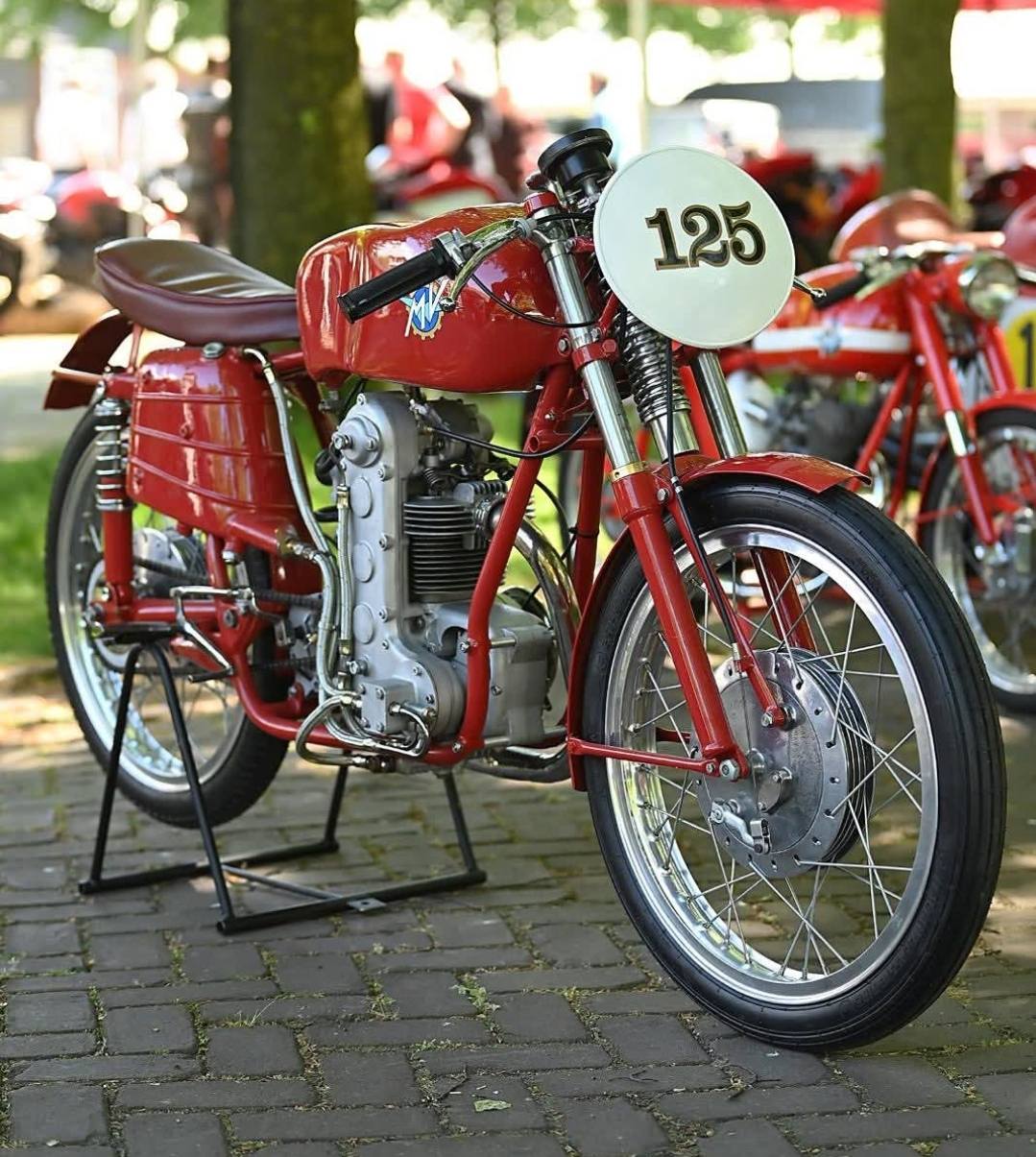 Vintage red MV Agusta 125 motorcycle with racing number plate on display stand