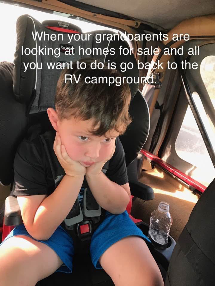 Young boy looking bored with chin on fists sitting in a car seat inside a vehicle