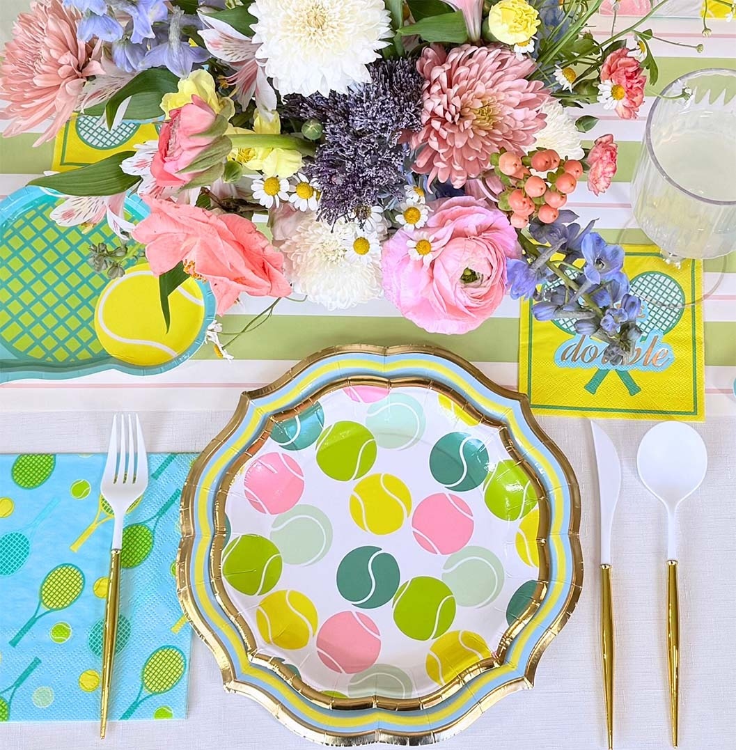 Overhead view of a colorful table setting with flowers, a decorative plate, napkins, and lemon accents