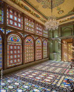 Ornate room with tall stained glass windows, crystal chandelier, decorative ceiling and patterned tile floor