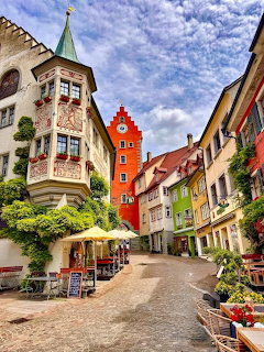 Cobblestone street with colorful historic buildings and red clock tower in Meersburg, Germany