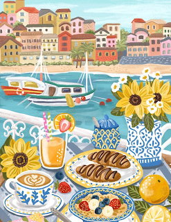 Brunch table with croissants, coffee, and sunflowers by a coastal village harbor with sailboats