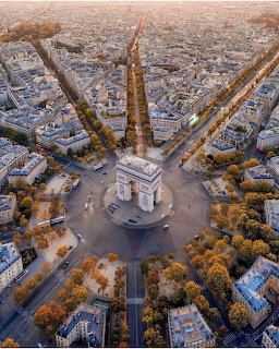 Aerial view of Arc de Triomphe surrounded by tree-lined avenues radiating outward in Paris