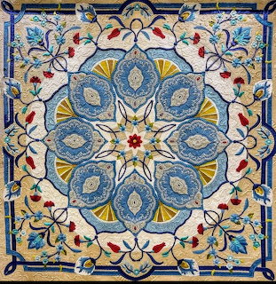 Ornate hand-sewn quilt with symmetrical blue and yellow floral mandala pattern on cream background