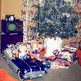 Vintage Christmas tree with ornaments surrounded by wrapped presents and toy car near old television