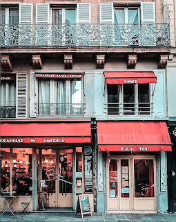 Traditional Parisian cafe storefronts with red awnings and ornate wrought-iron balconies above