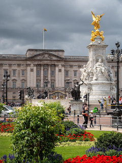 Buckingham Palace facade with Victoria Memorial gold statue and flower gardens in foreground