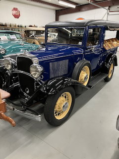 Restored vintage blue antique pickup truck with yellow spoke wheels in an indoor showroom