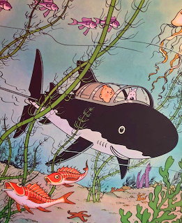 Illustration of Tintin and Snowy in a shark-shaped submarine underwater with fish and seaweed