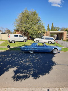 Blue classic convertible car parked on suburban street with tree shadow