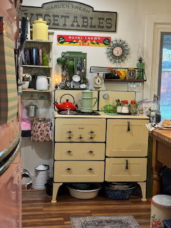 Vintage cream-colored stove in a retro kitchen with colorful kettles, signs, and antique decor items