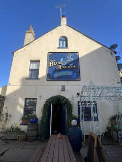 Exterior of a cream-colored pub building with a sign above the doorway and blue sky