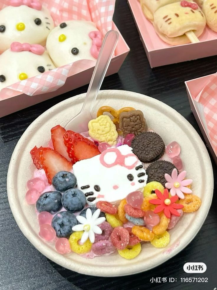 Bowl of colorful dessert with Hello Kitty decorations, strawberries, blueberries, and cereal on checkered tablecloth