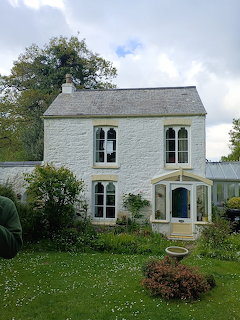 White two-story cottage with traditional architecture in green garden setting