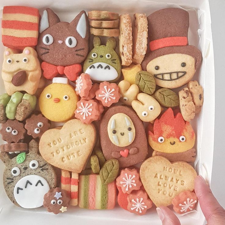Variety of decorated cookies with anime character designs in a white box