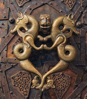 Ornate antique metal door with two symmetrical dragon-shaped knockers