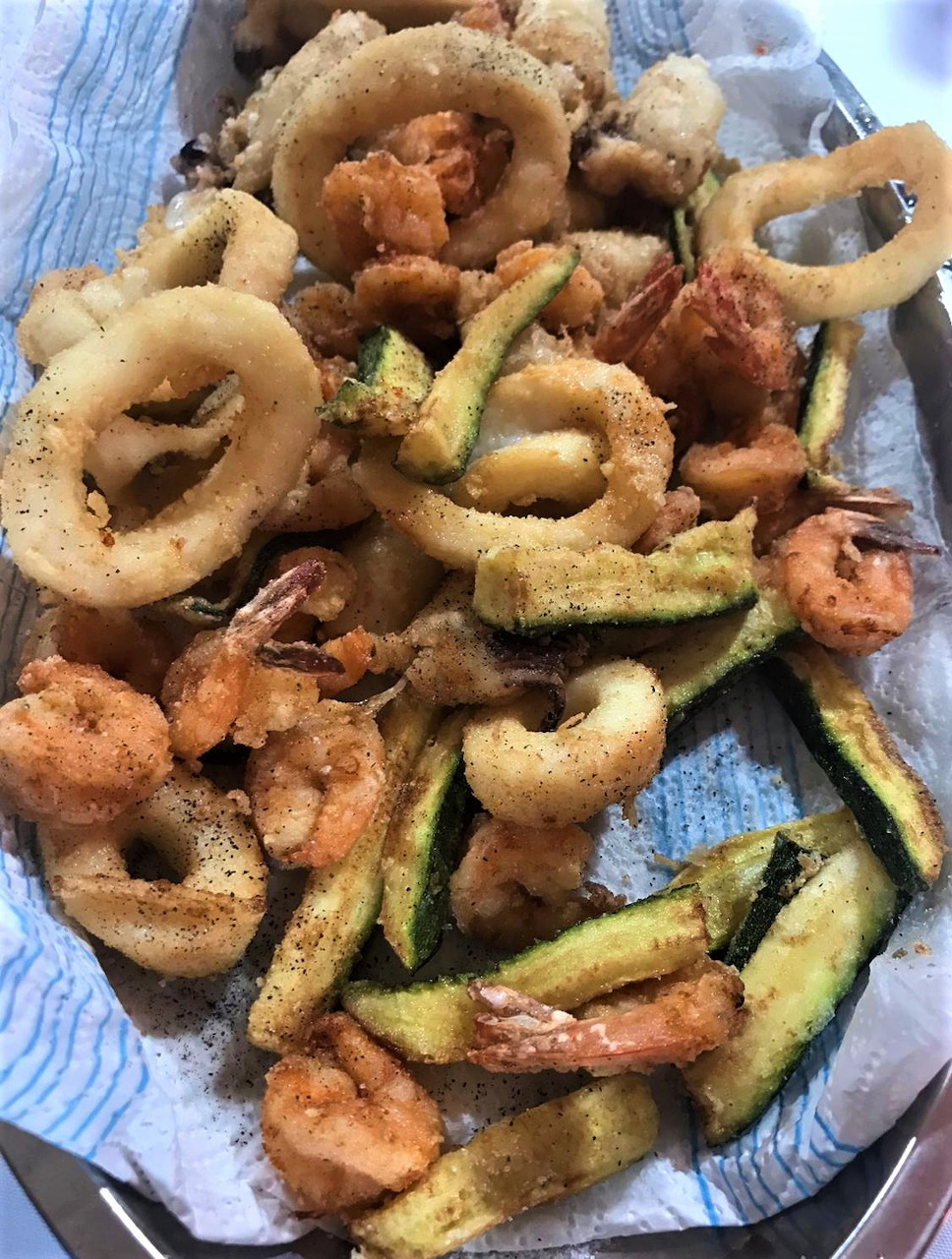 Plate of fried seafood with calamari rings, shrimp, and zucchini on white dish