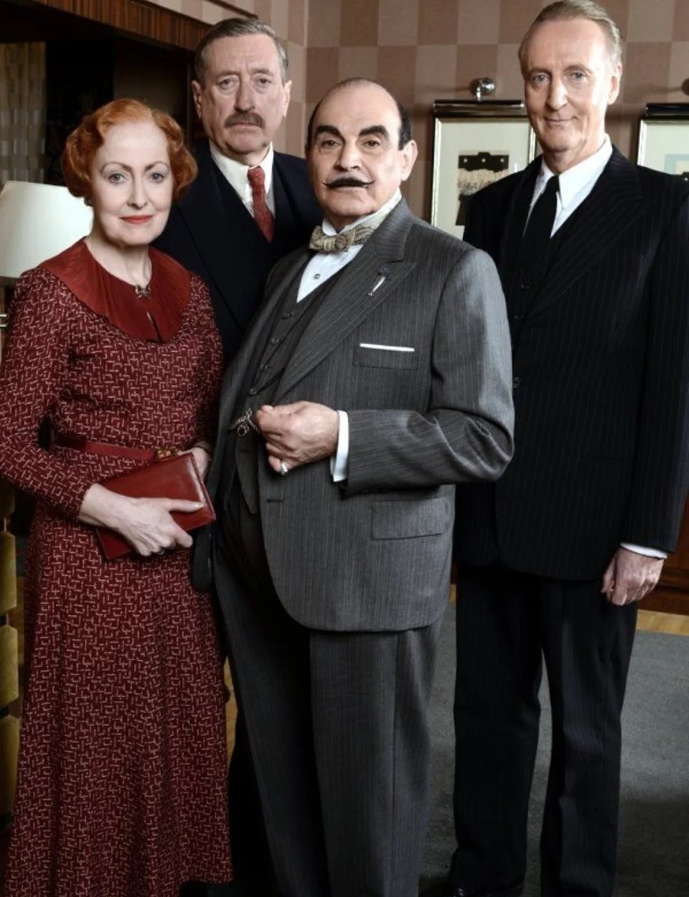 Four actors from Poirot TV series standing together in period costumes indoors