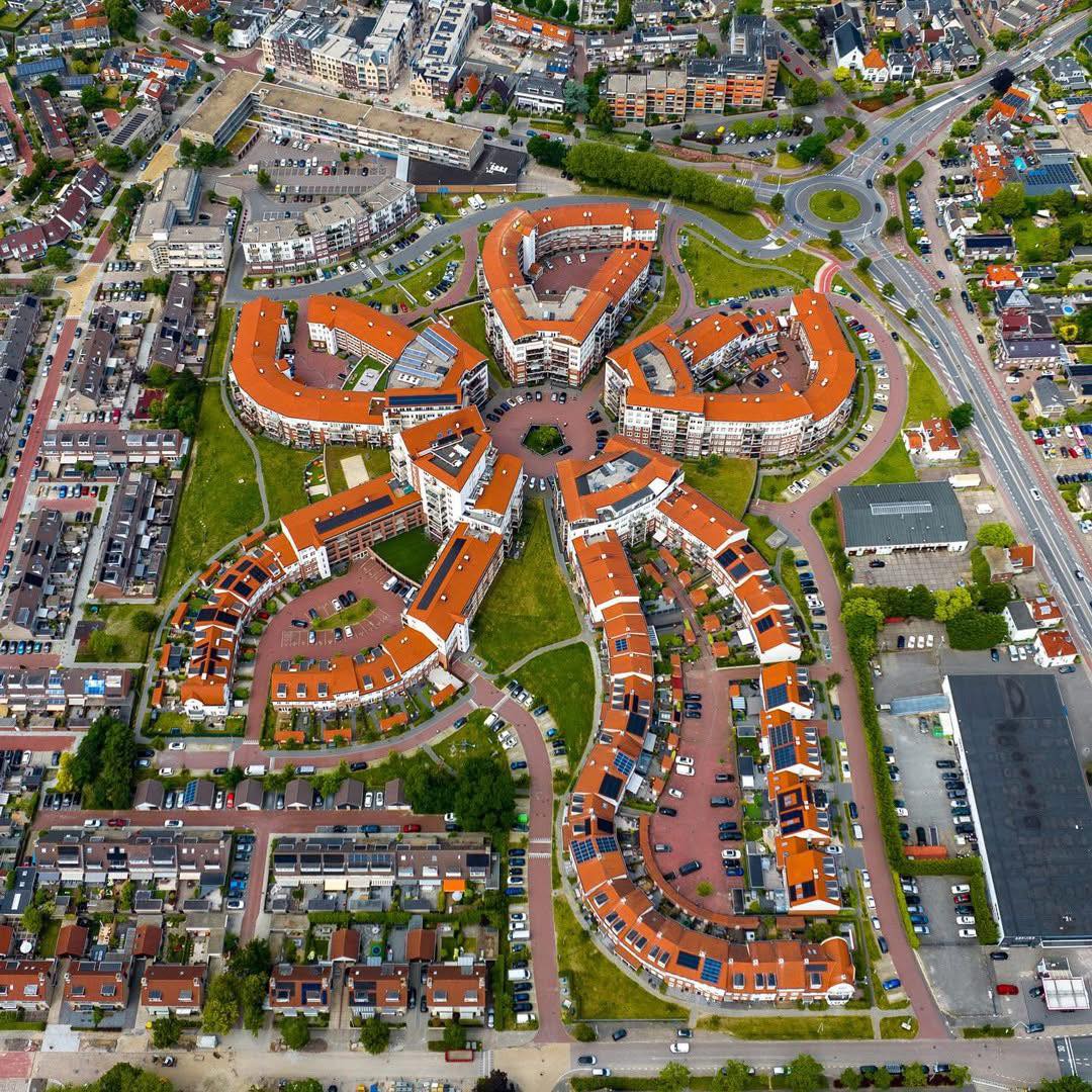 Aerial photograph of Dutch residential area with buildings arranged in a symmetrical flower pattern with orange roofs
