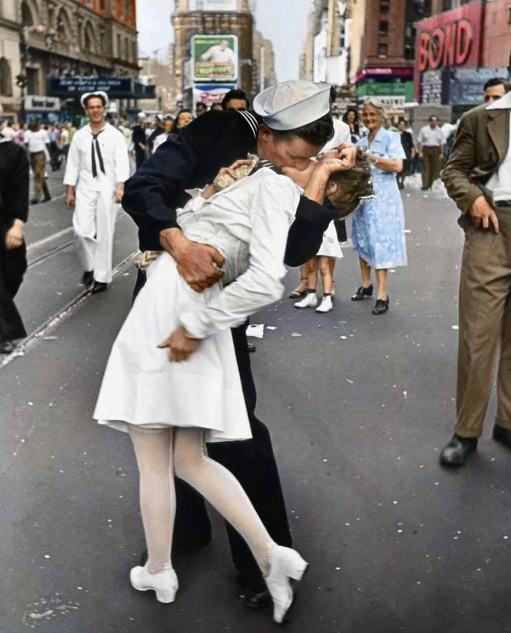 A sailor kissing a nurse in Times Square while people watch on a city street