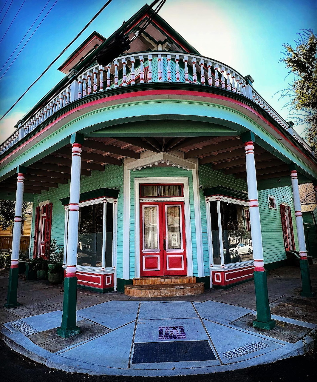 Historic corner storefront with turquoise facade, red doors, wraparound porch and decorative balcony in New Orleans