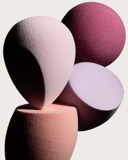 Abstract arrangement of pink and mauve makeup sponge shapes on a light background