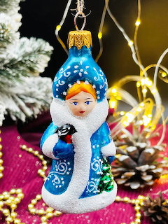 Glass Snow Maiden Christmas ornament in blue coat with pine branches and golden bead garland