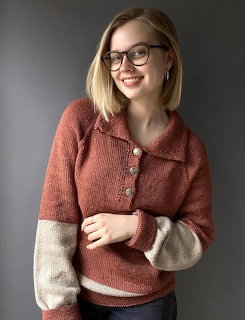 Smiling young woman with glasses in a rust knit sweater with cream sleeves